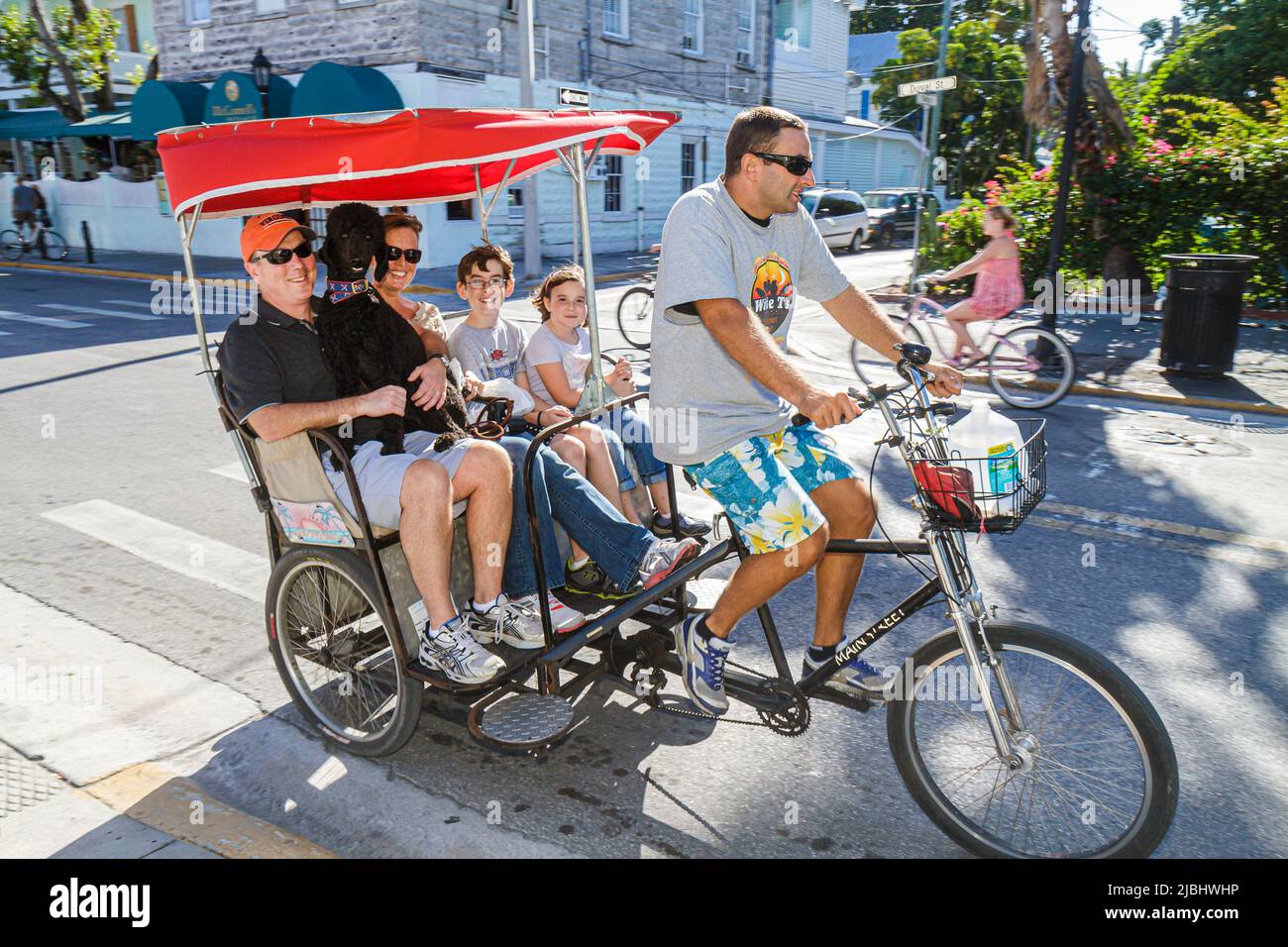 Key West Florida Keys Duval Street,bicycle taxi pedicab driver father mother dog,boy girl kids children family parents brother sister Stock Photo