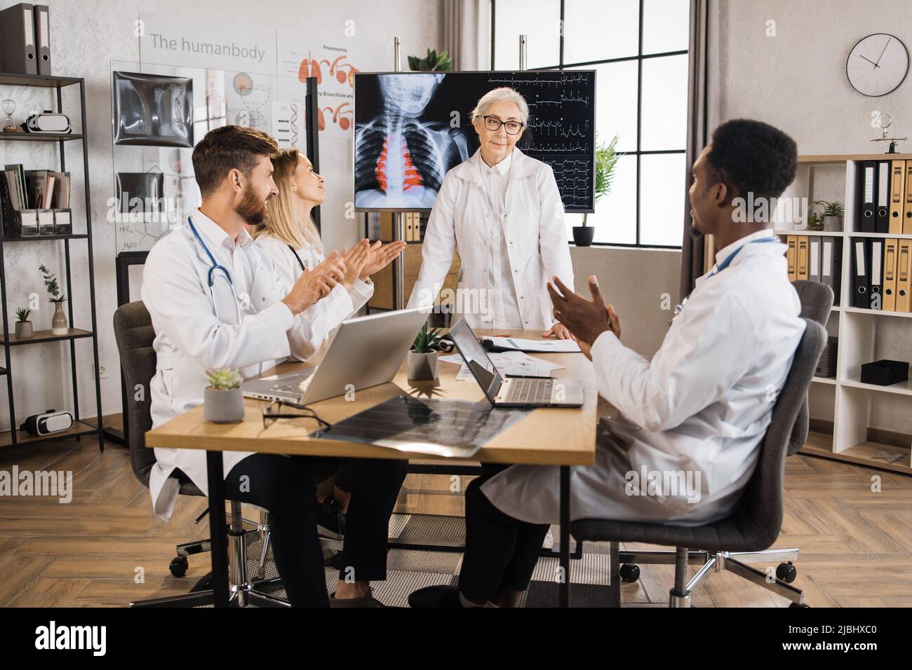Group of diverse therapists clapping in hands after successful speech of female head doctor at