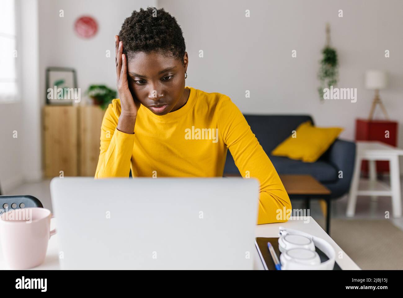 Worried young african woman using laptop at home Stock Photo
