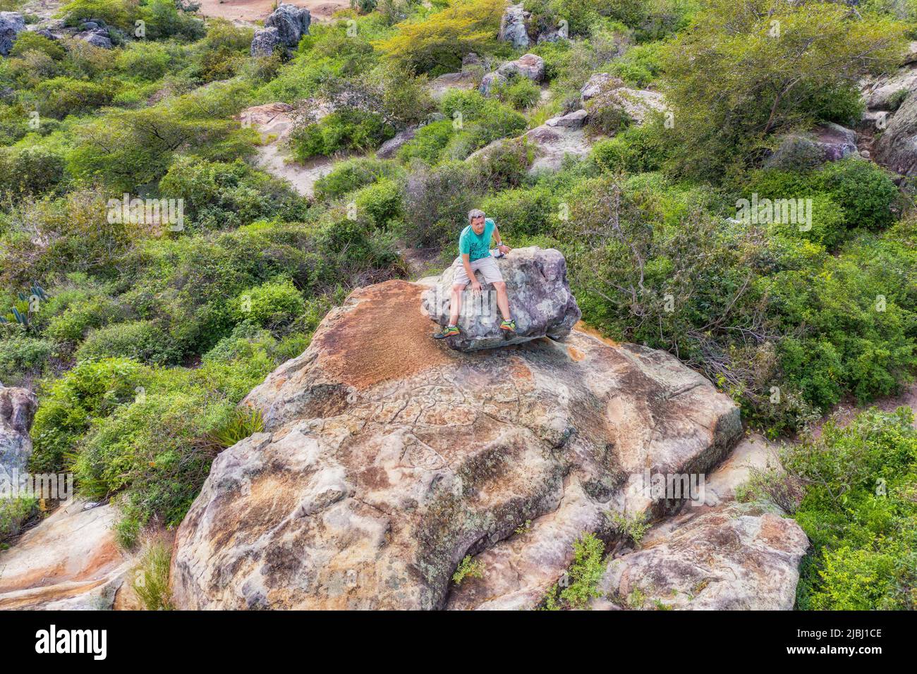 Aerial view of a man sitting on top of a rocky plateau in Tobati, Paraguay. Stock Photo
