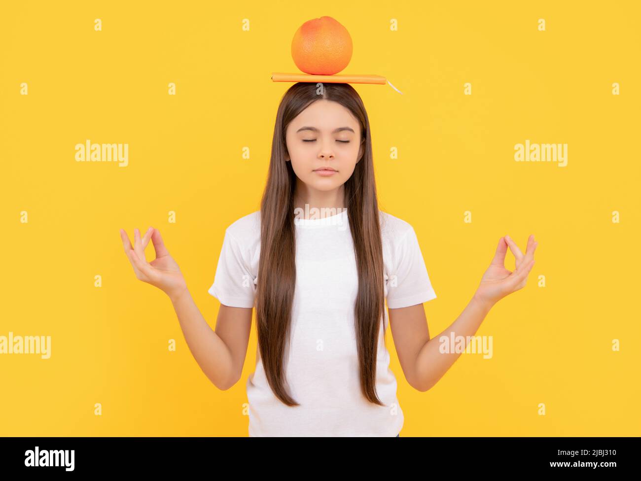 calm child with grapefruit and book on yellow background, health Stock Photo