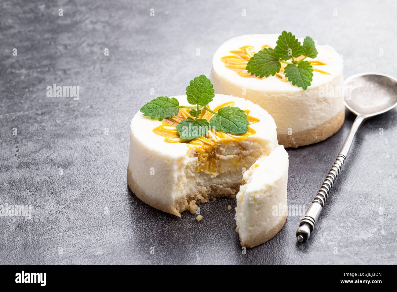 Mini  Cheesecakes decorated with yellow jam on gray background Stock Photo