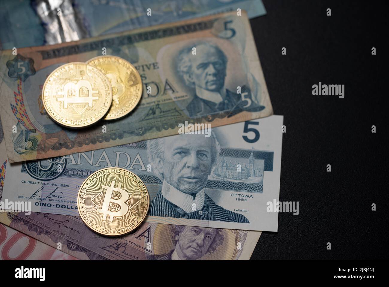 Toronto, Canada - October 30. 2021: Bitcoin on old Canadian Dollar banknotes. BTC and CAD money, Trading Bitcoin in Canada concept Stock Photo