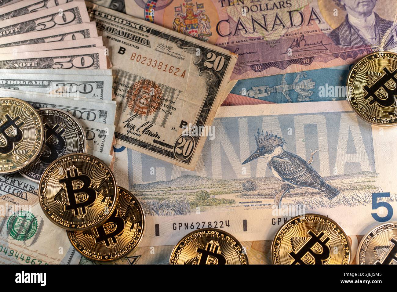 Toronto, Canada - October 30. 2021: Bitcoin on Canadian and US Dollar banknotes, modern and old monetary systems. Historic 20 USD bill next to BTC and Stock Photo
