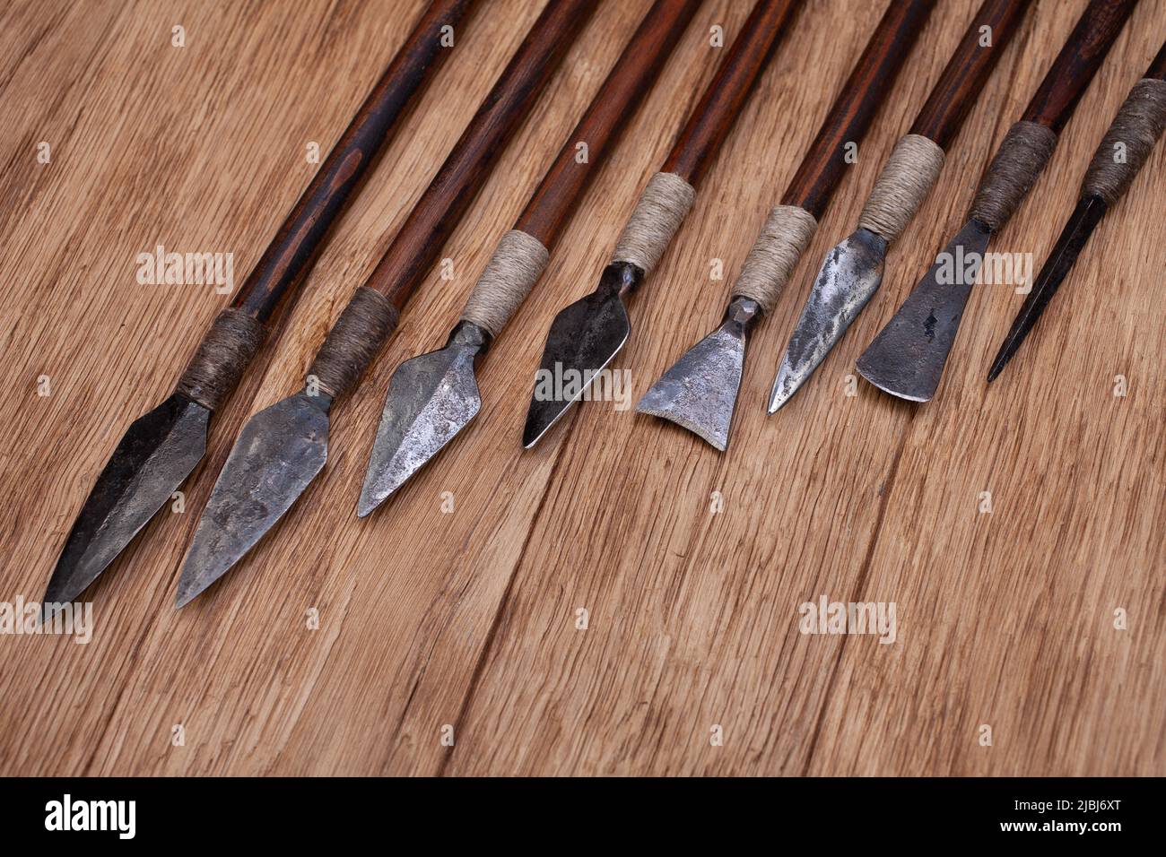 Different types of arrowheads made of iron on wooden background. Stock Photo