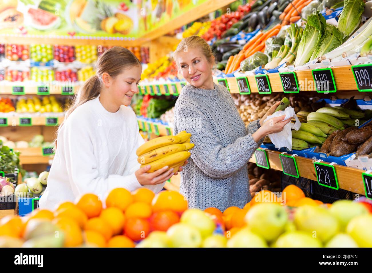 Portrait of teenage girl and mother who buying fresh vegetables and ...