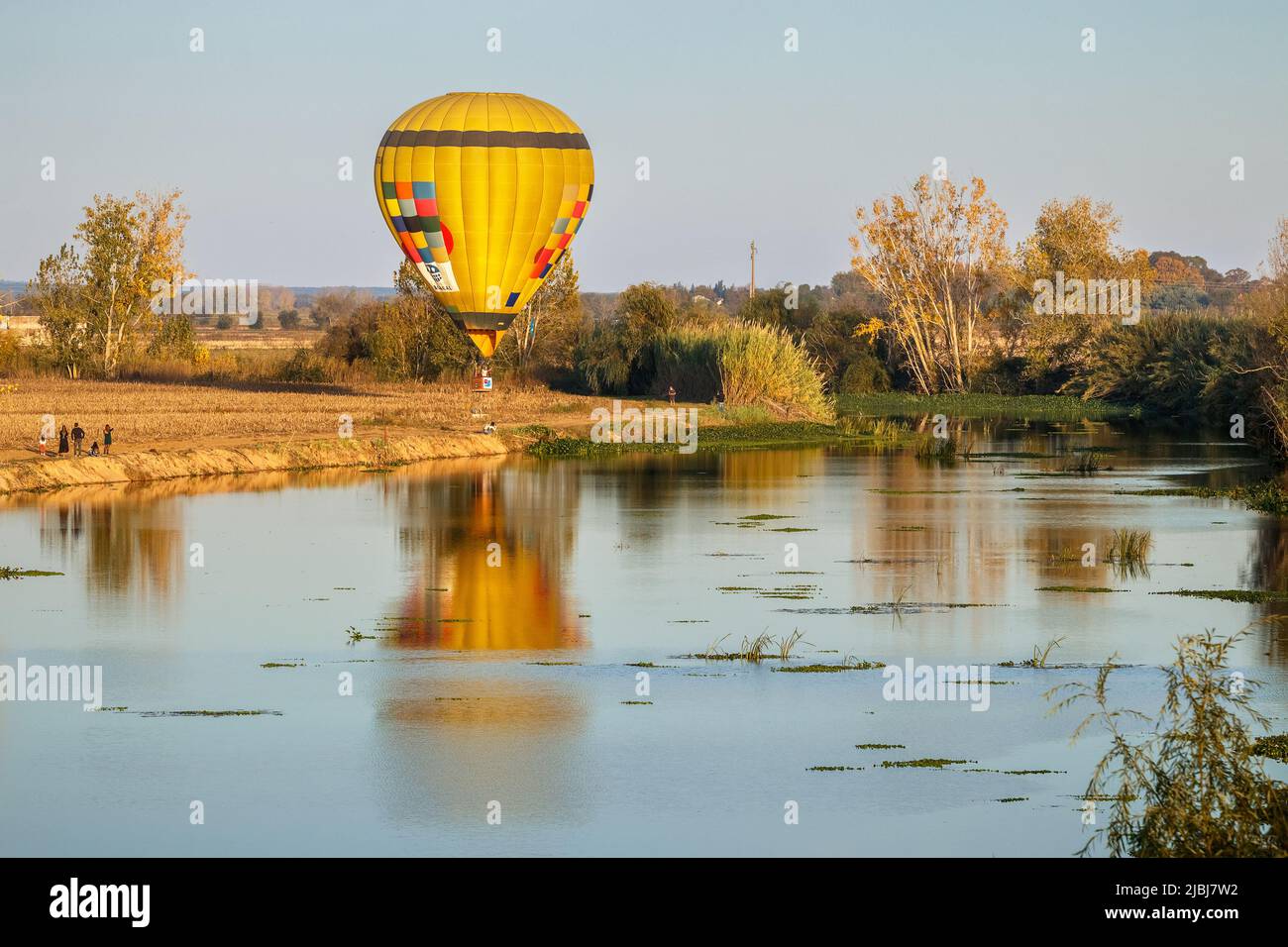 Coruche, Portugal - November 13, 2021: View over the Sorraia River in Coruche, Portugal, with a hot air balloon flying low to the ground. Stock Photo
