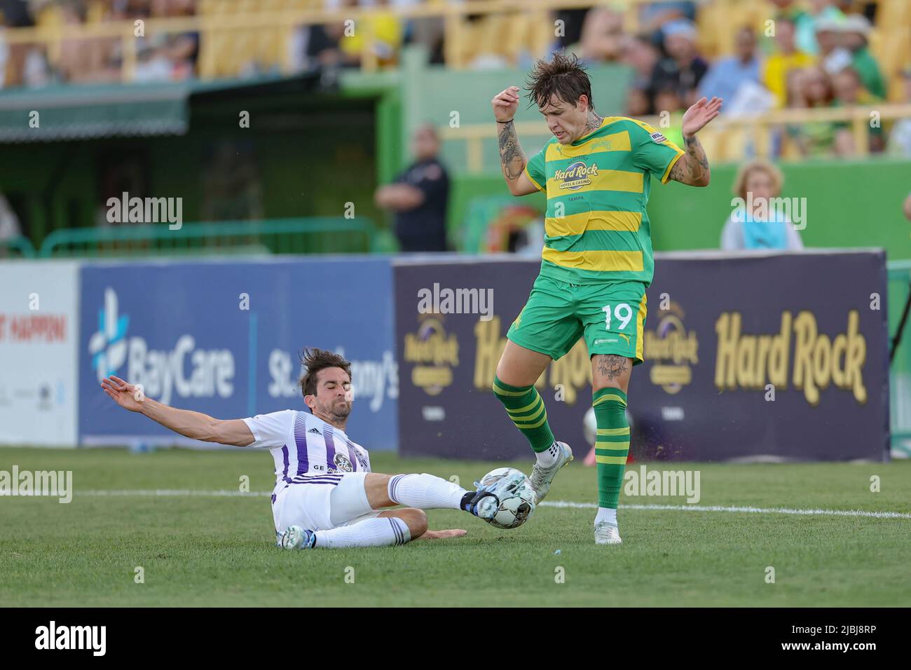 St. Petersburg, FL: Louisville City FC midfielder Tyler Gibson (12) slide tackles and trips up Tampa Bay Rowdies forward Jake LaCava (19) during a USL Stock Photo