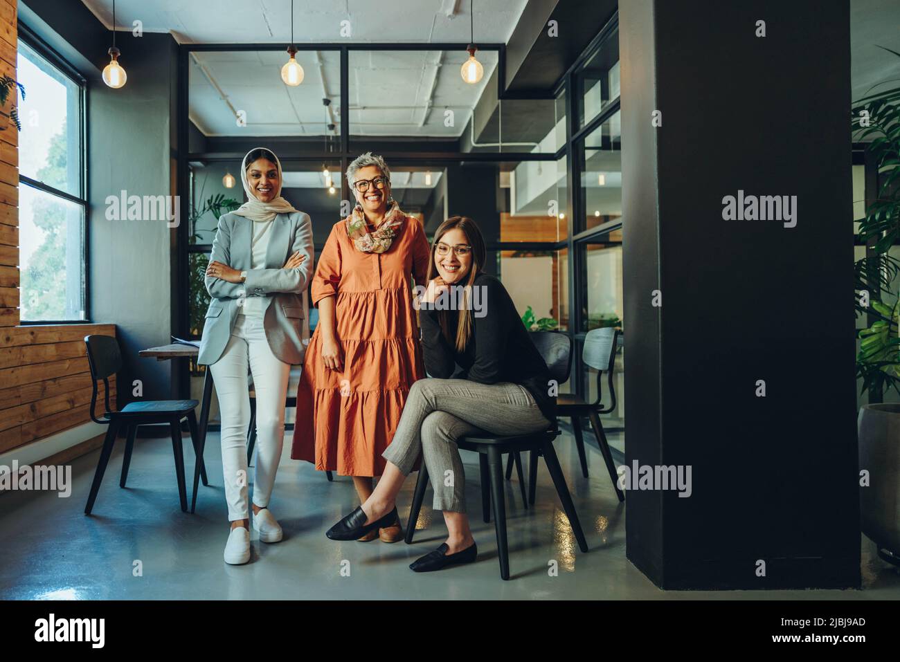 Multiethnic entrepreneurs smiling at the camera in a boardroom. Group of successful businesswomen working as a team in an inclusive workplace. Diverse Stock Photo
