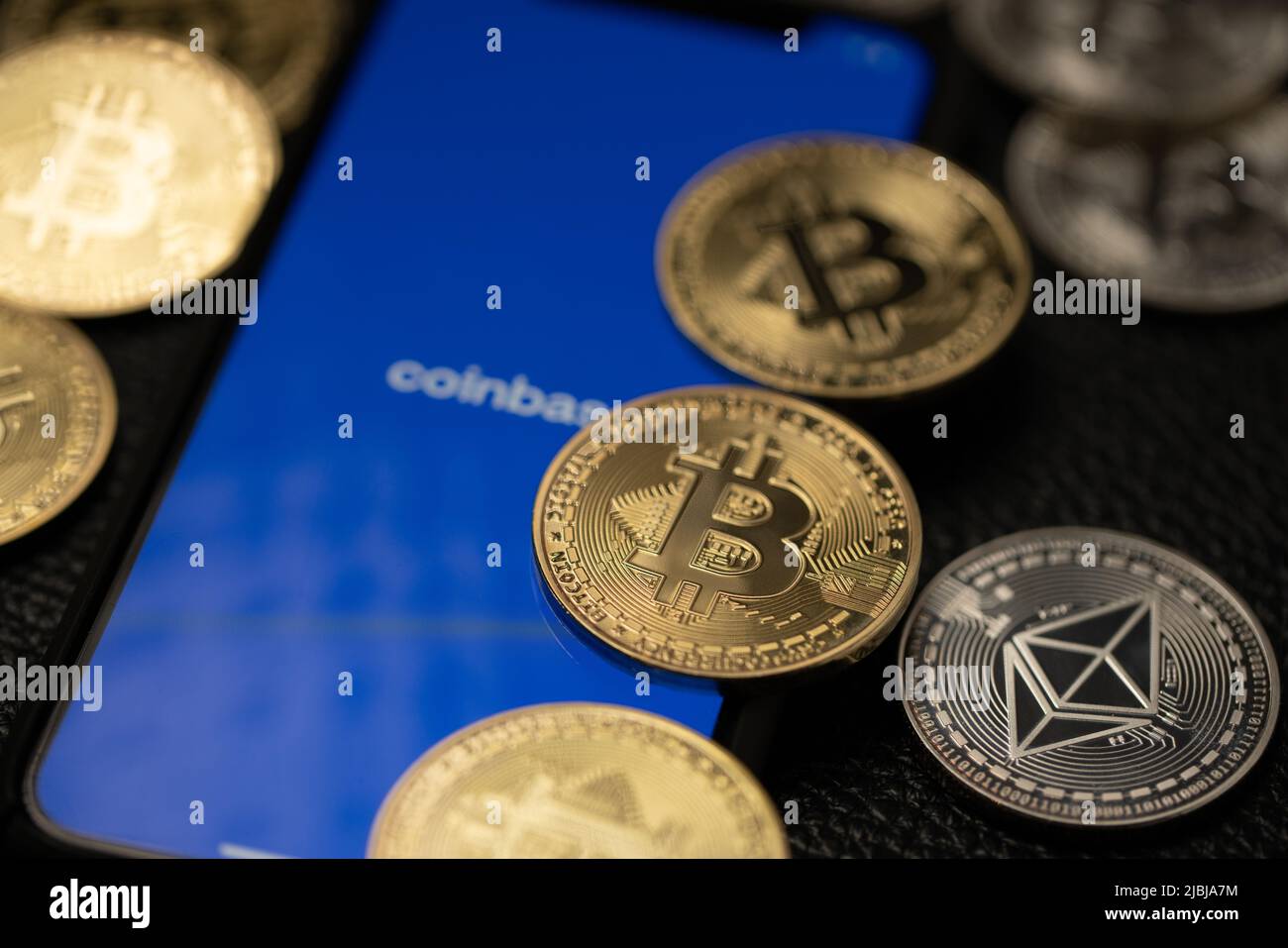 Bolzano, Italy - April 10. 2021: Smartphone with coinbase app running surrounded by gold bitcoin and silver ethereum coins Stock Photo