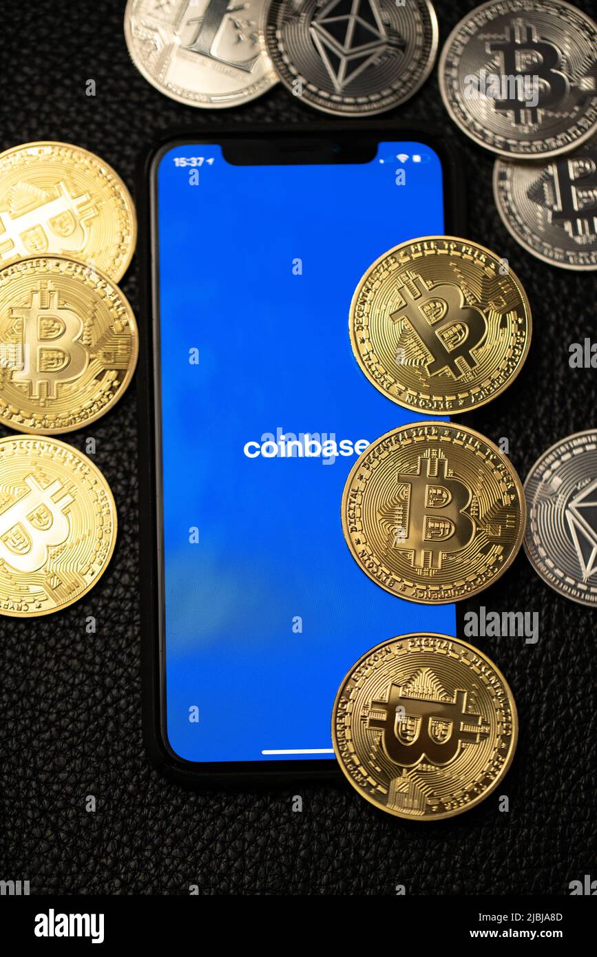 Bolzano, Italy - April 10. 2021: Coinbase app on smartphone next to bitcoin and ethereum coins on leather background Stock Photo
