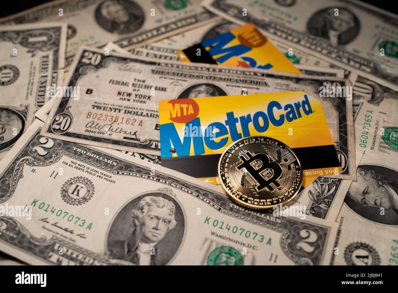 Manhattan, New York/USA - March 26. 2021: Bitcoin on NYC Metro card and dollar banknotes. Purchasing public transport ticket with cryptocurrency or US Stock Photo