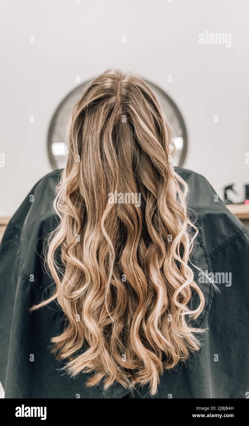 Healthy Long blonde Shiny Wavy hair back view. Volume shampoo. Blond Curly permed Hair. Beauty salon and hair care concept. High quality photo Stock Photo