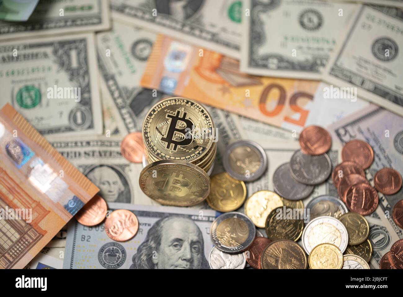 Bitcoins piled up on top of dollar and euro banknotes. Gold BTC coins with dollar coins, trading crypto concept Stock Photo
