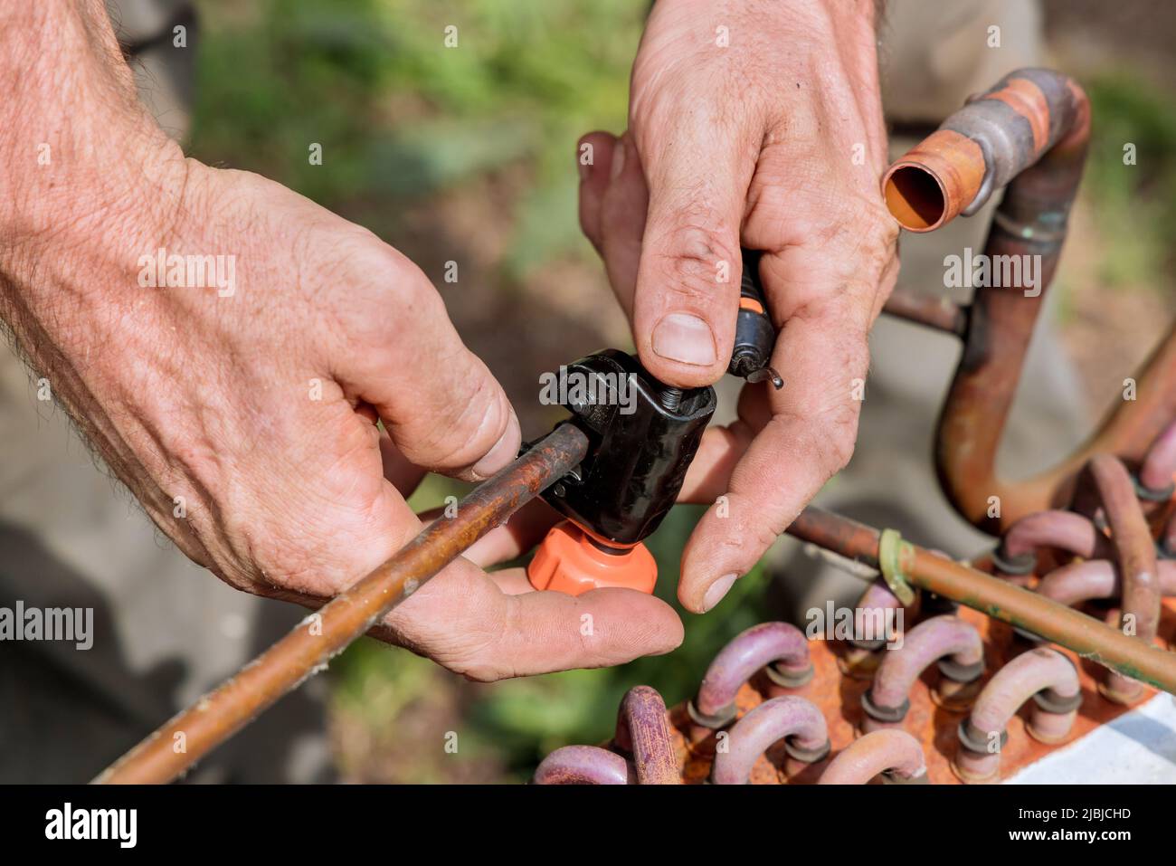 Using pipe cutter to cut copper pipe outside Stock Photo Alamy