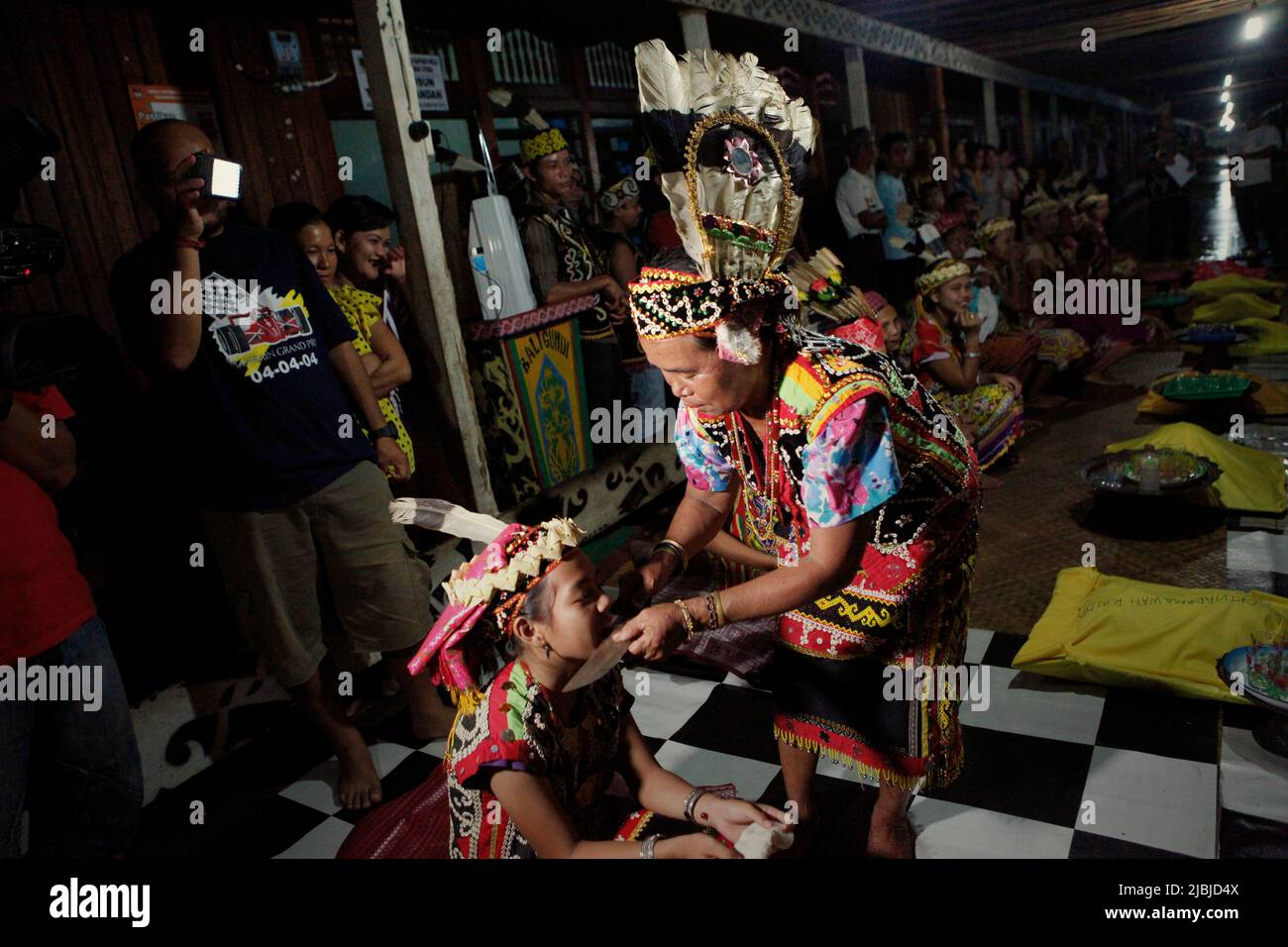 A senior woman conducting a ritual with a child, a part of a welcome ceremony during an ecotourism event at Bali Gundi longhouse of traditional Dayak Taman community in Sibau Hulu, Putussibau Utara, Kapuas Hulu, West Kalimantan, Indonesia. Stock Photo