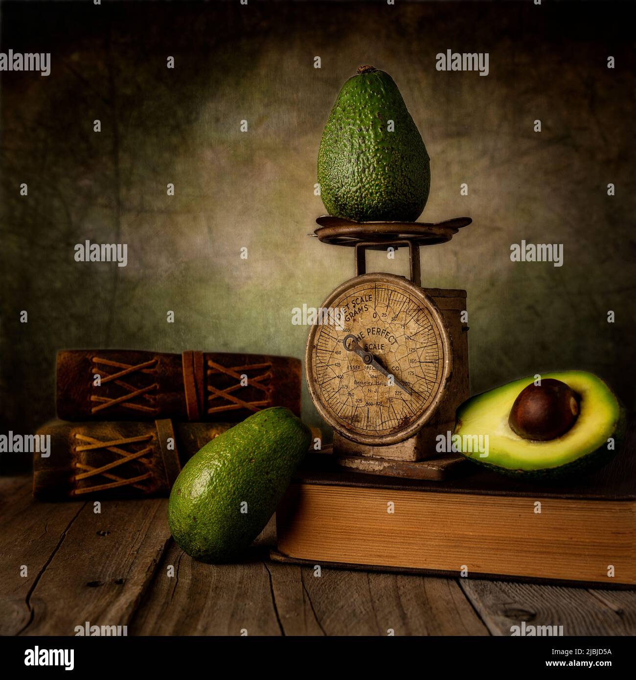 Avocado with smal vintage scale on table with old books still life photography Stock Photo