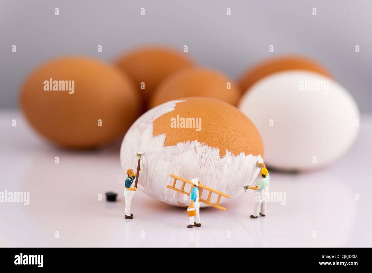 Miniature people small model human figure painting brown Eggs to white Stock Photo