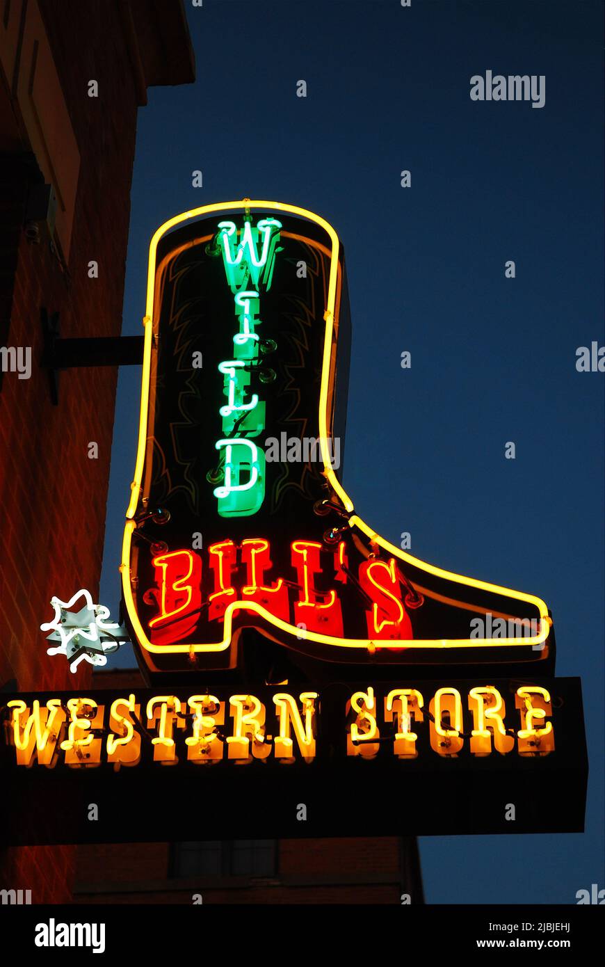 A large sign with neon lights, shaped like a cowboy boot lures customers into a western store in Dallas Texas Stock Photo