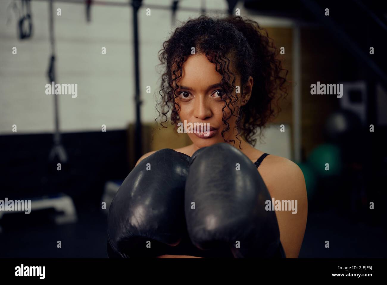 African American female boxer training at the gym with boxing gloves on. Mixed race female holding boxing gloves in air. High quality photo Stock Photo