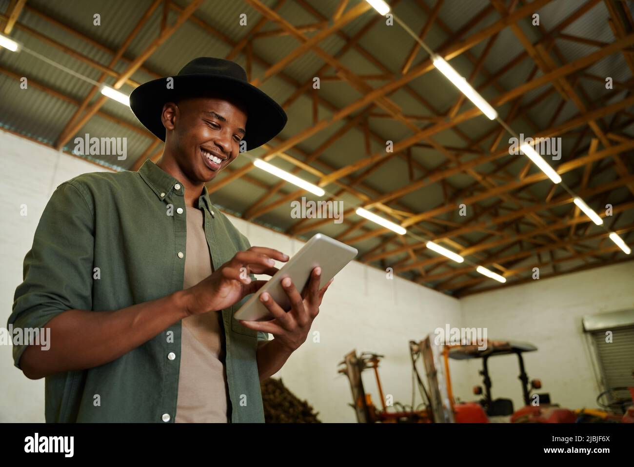Mixed race male farmer typing on digital tablet standing in farm dairy  Stock Photo