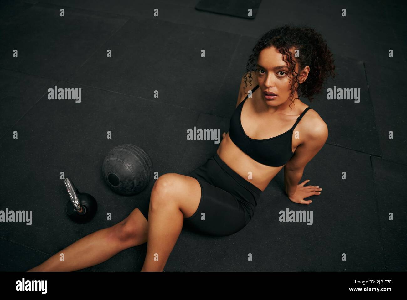 African American female holding skipping rope in the gym. Female athlete looking to the camera during exercise. High quality photo Stock Photo