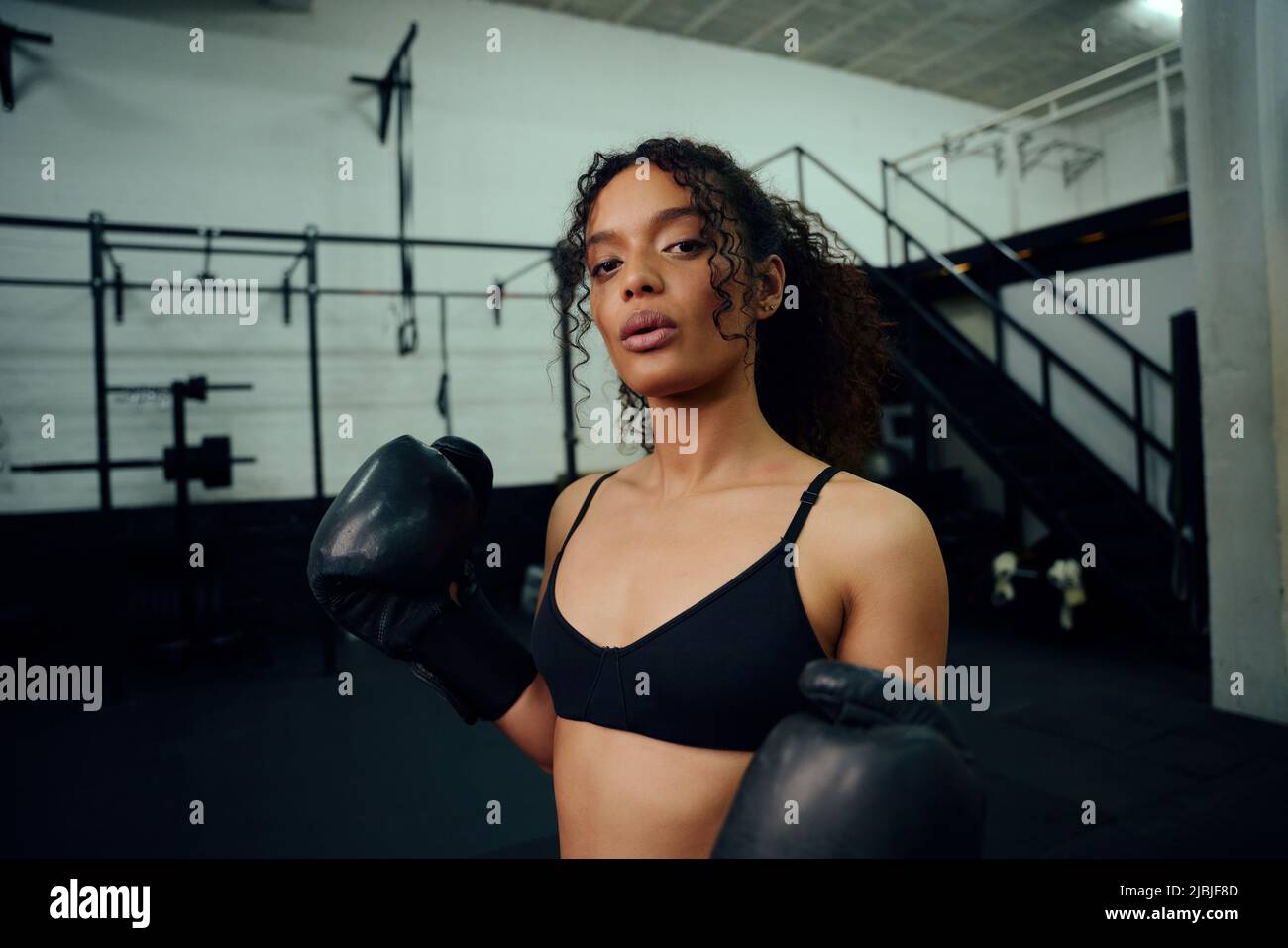 African American female boxer training at the gym with boxing gloves on. Mixed race female holding boxing gloves in air. High quality photo Stock Photo