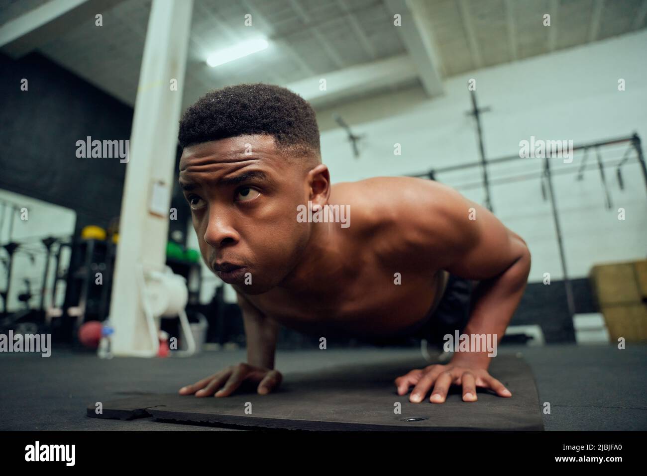 Young African American male doing push-ups in the gym. Mixed race, male personal trainer doing cross fit indoors. High quality photo Stock Photo