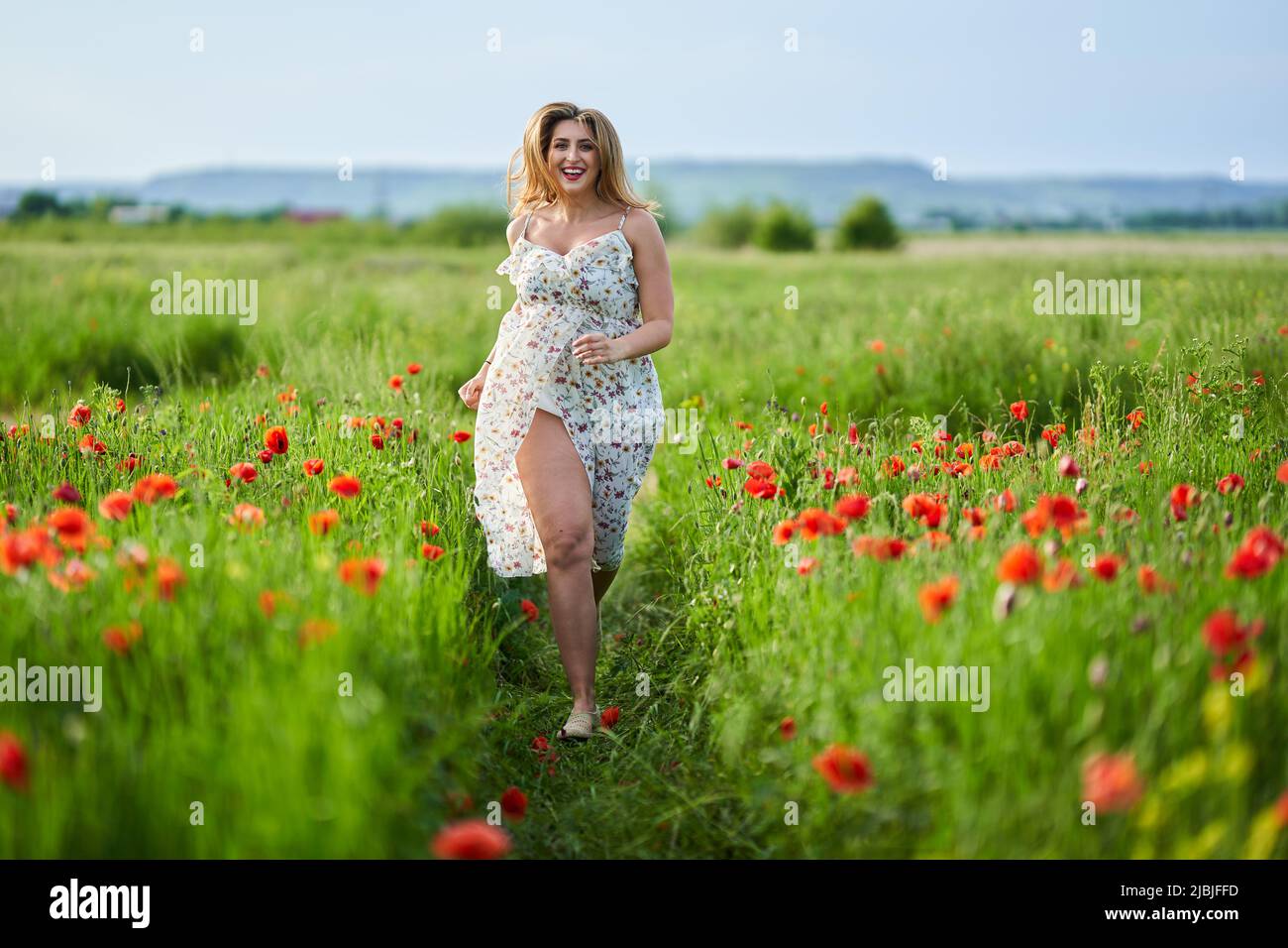 Beautiful plus size young indian woman in floral dress in a poppy field ...