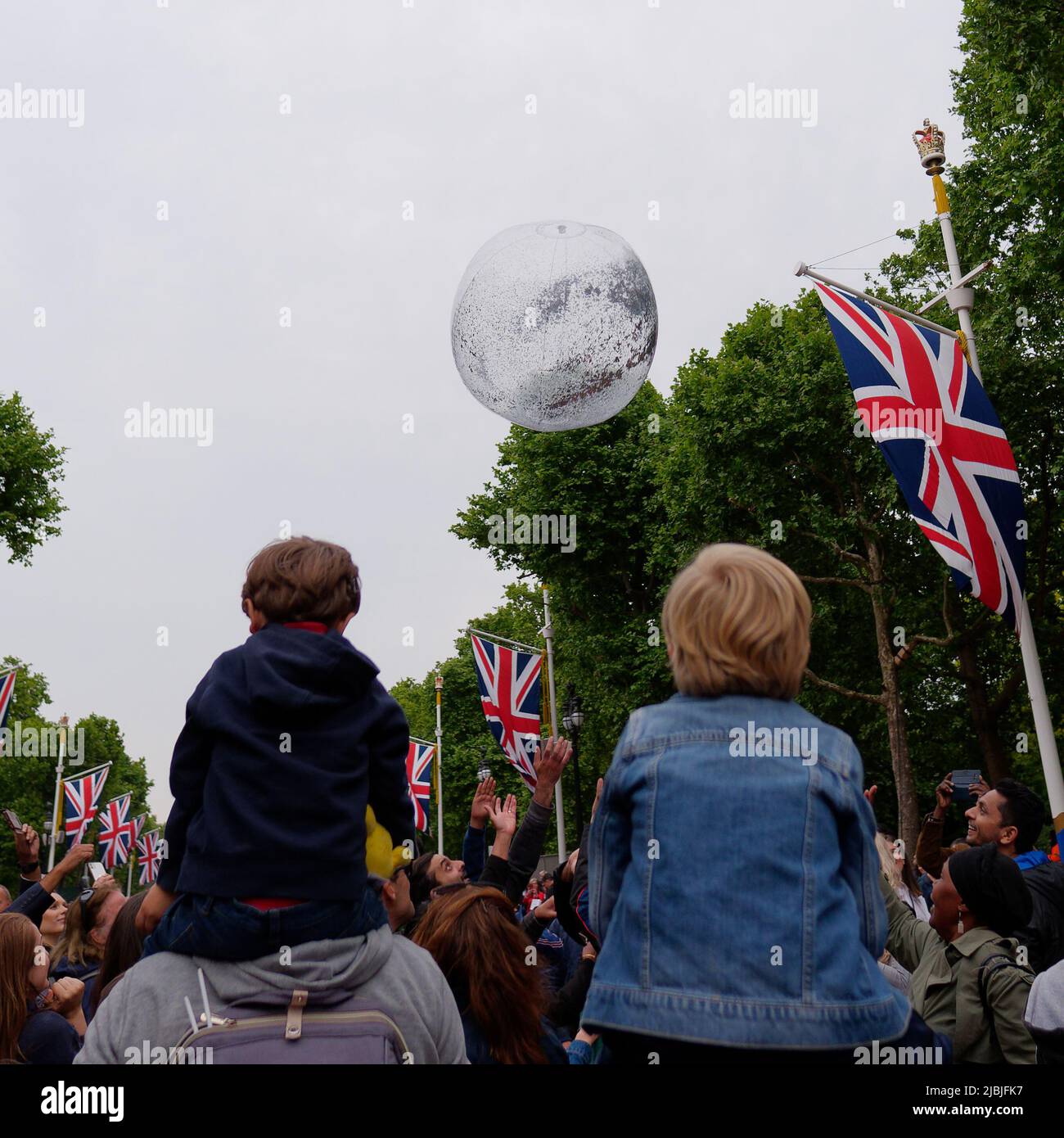 London, Greater London, England, June 04 2022: Jubilee Concert at The Mall. Boys sit on shoulders as people try to hit the ball down the street. Stock Photo