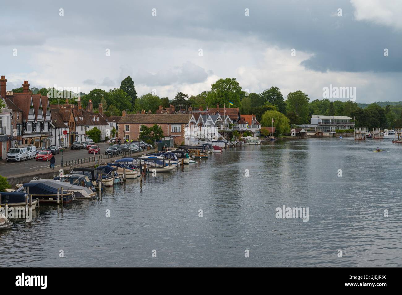 View along the River Thames from Henley Bridge on a dull, cloudy day. Rowers on the water in double scull. Henley on Thames, Oxfordshire, England, UK Stock Photo