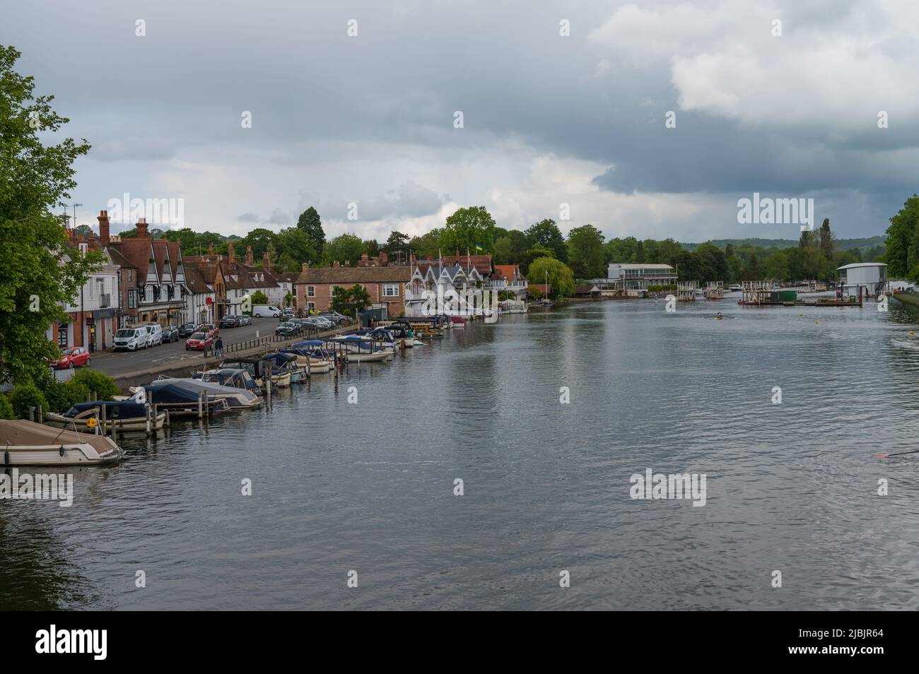 View along the River Thames from Henley Bridge on a dull, cloudy day. Rowers on the water in double scull. Henley on Thames, Oxfordshire, England, UK Stock Photo