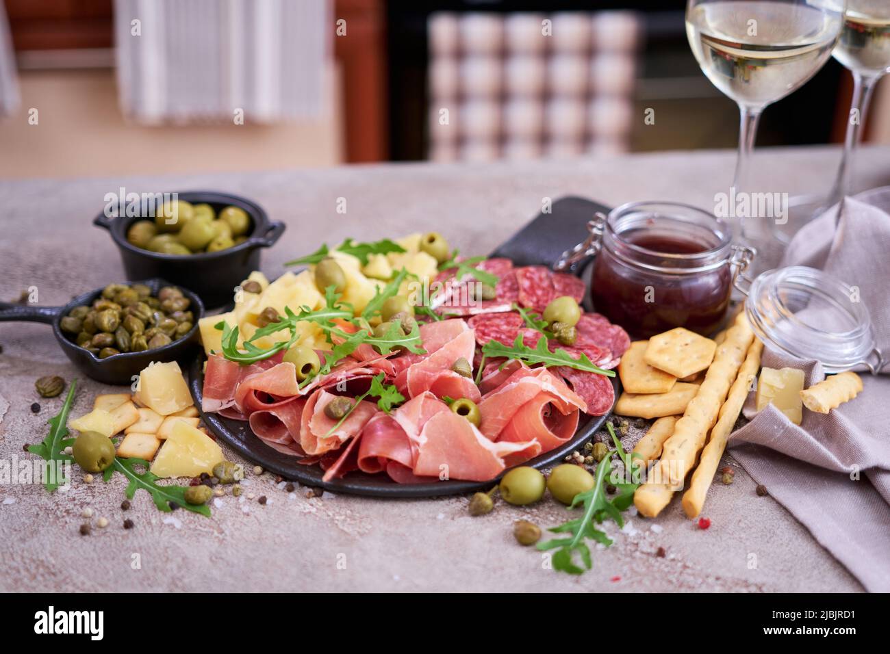 Two glasses of white wine and Italian antipasto meat platter on