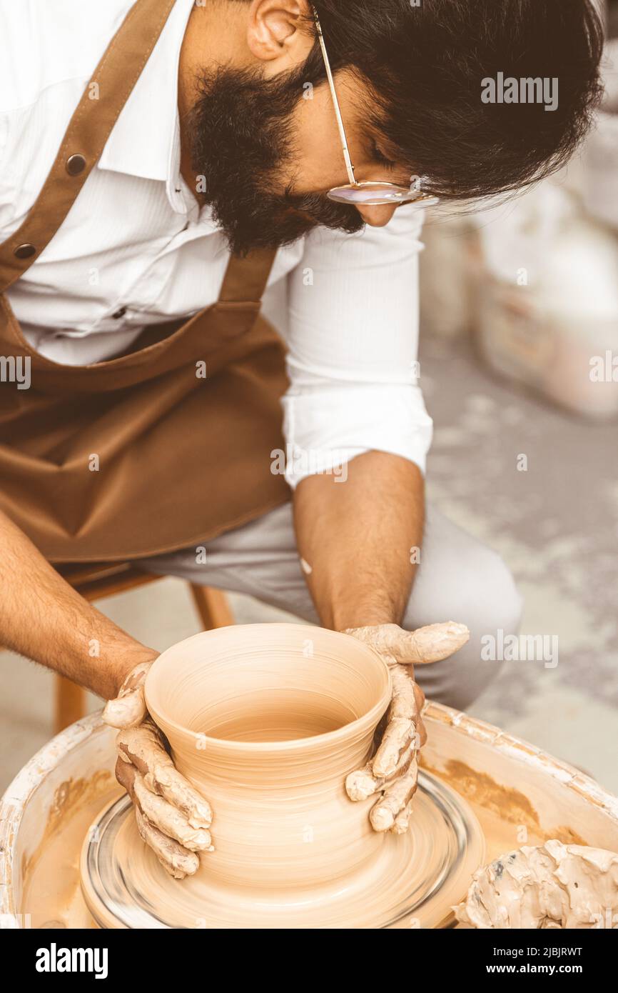 A young male potter is engaged in craft in his on a potter's