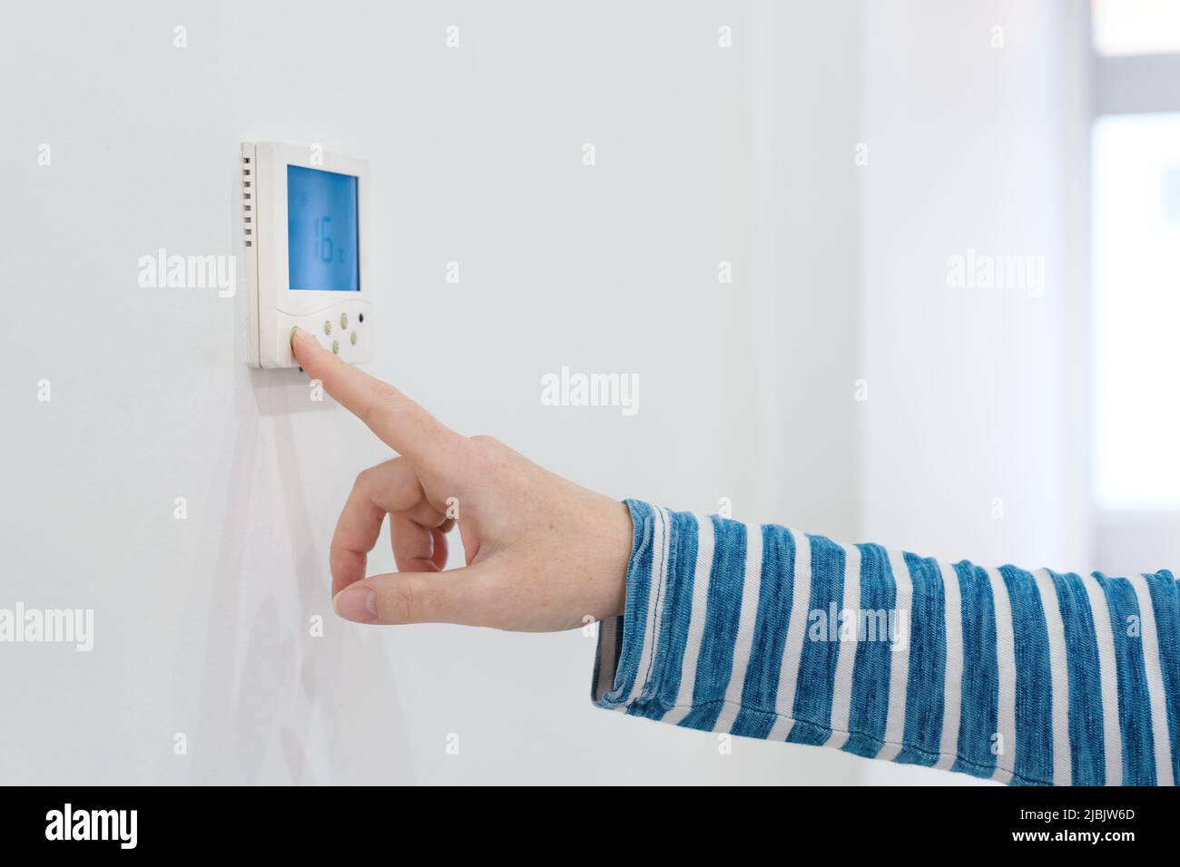 Female hand using of home heating and cooling system control unit, selective focus Stock Photo