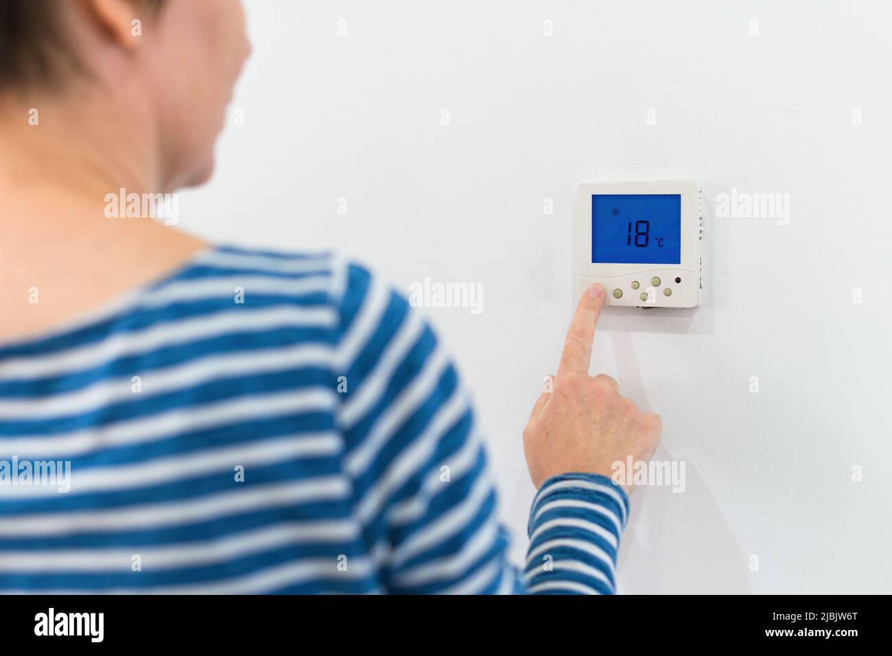 Female hand using of home heating and cooling system control unit, selective focus Stock Photo