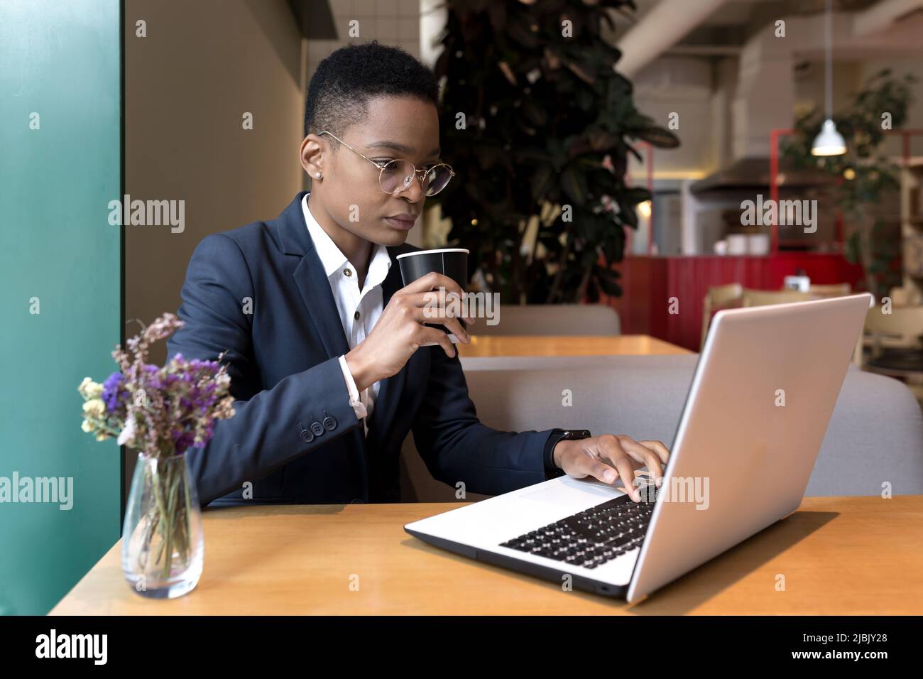 Serious and focused business woman working in a hotel restaurant, African American woman traveling on a business trip Stock Photo