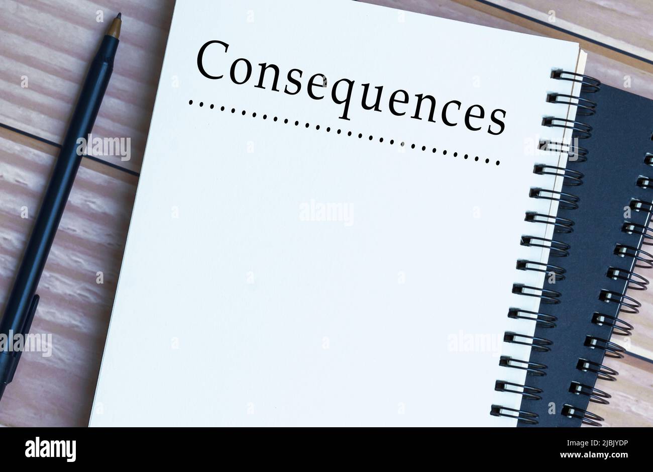 Consequences word written on notepad on wooden desk. Negative, positive, bad and good result concept. Stock Photo