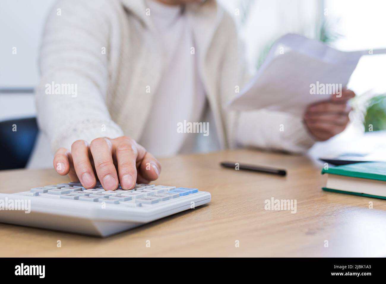 Man using calculator at wooden table Stock Photo