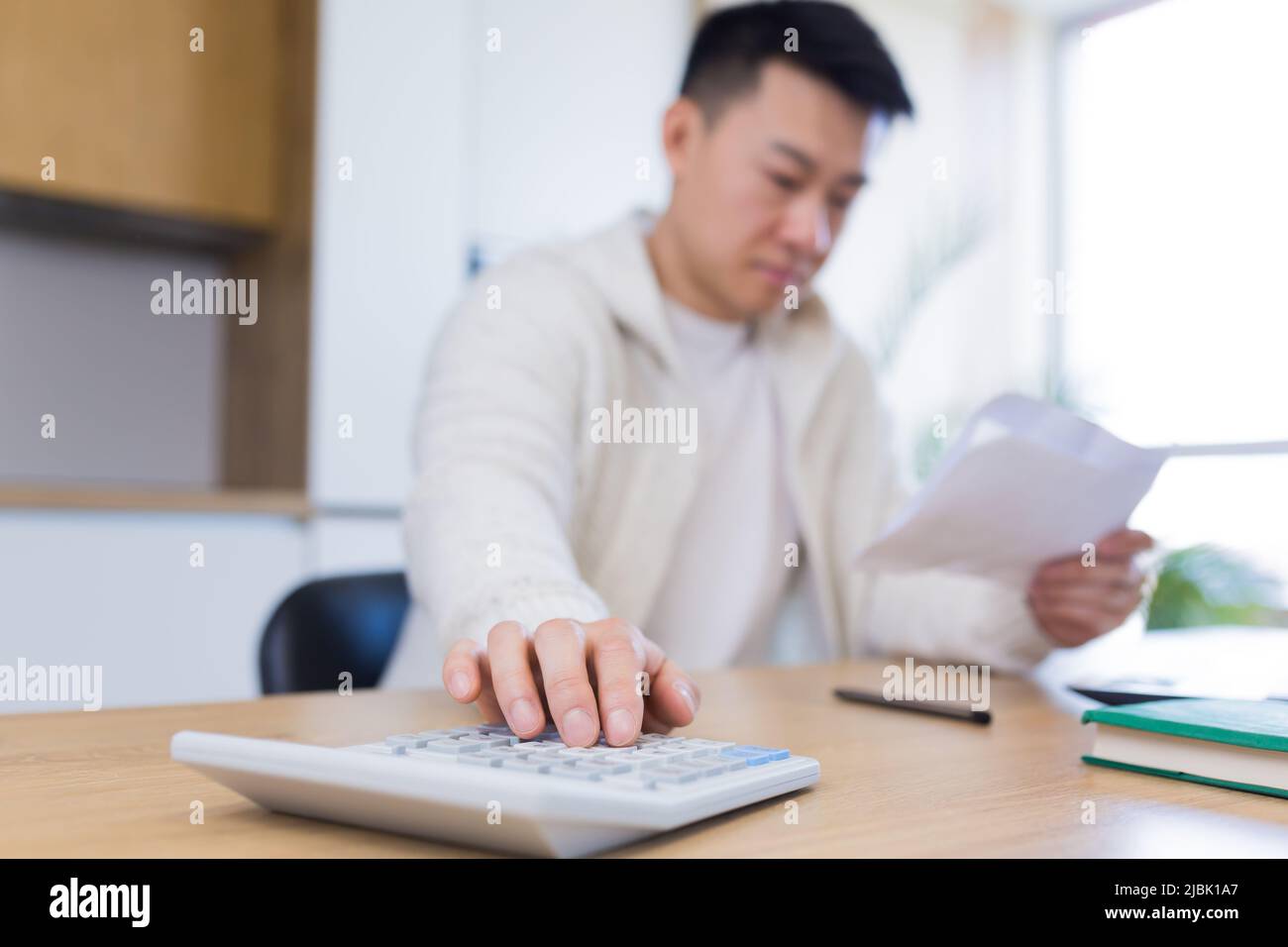 Man using calculator at wooden table Stock Photo