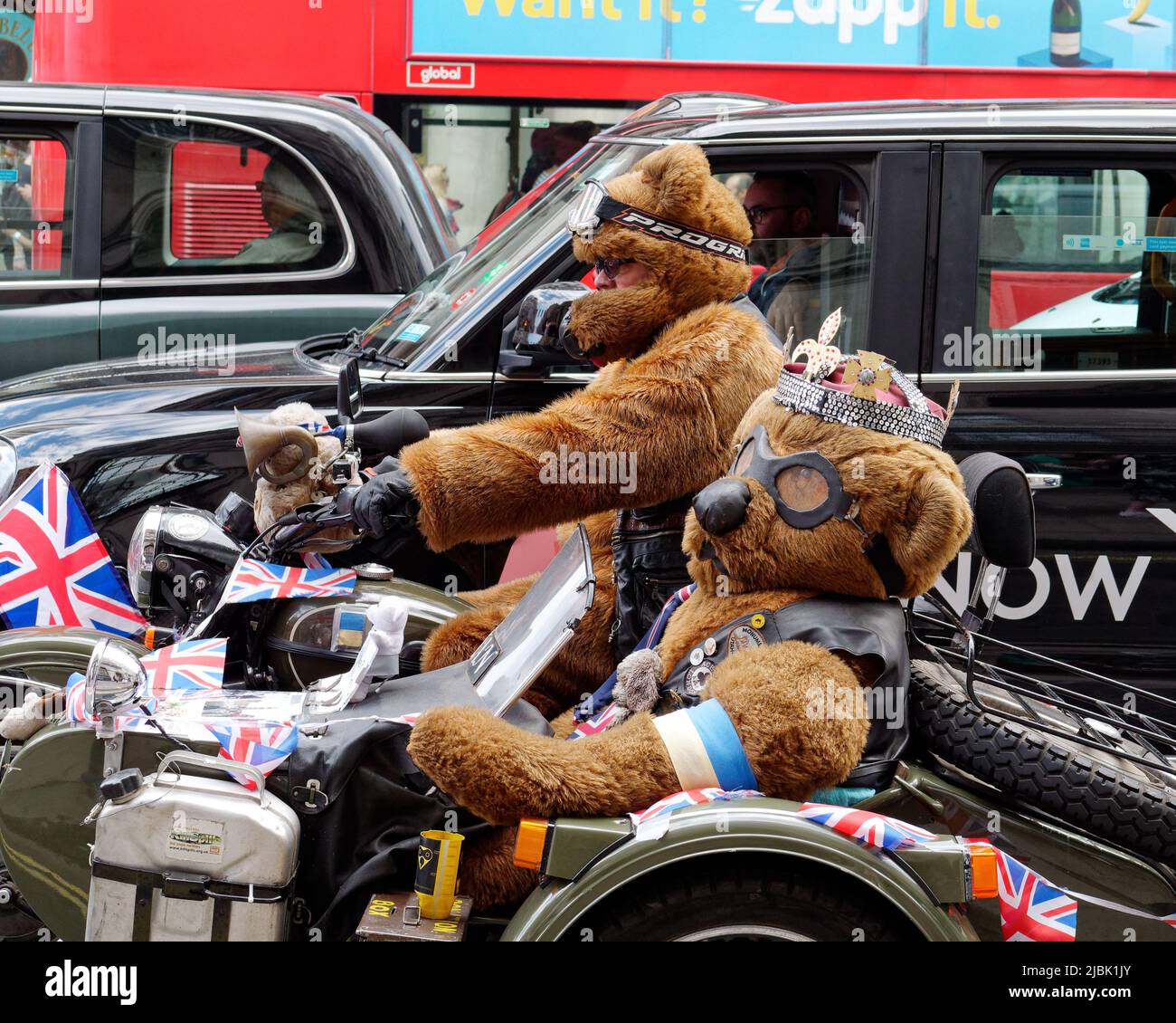 London, Greater London, England, June 04 2022: People in bear costumes driving a motor cycle and side car with Union Jacks on Piccadilly. Stock Photo