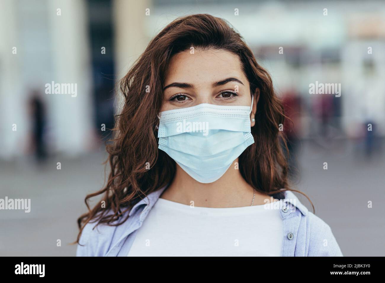 Portrait of young beautiful woman in blue medical mask on the street ...