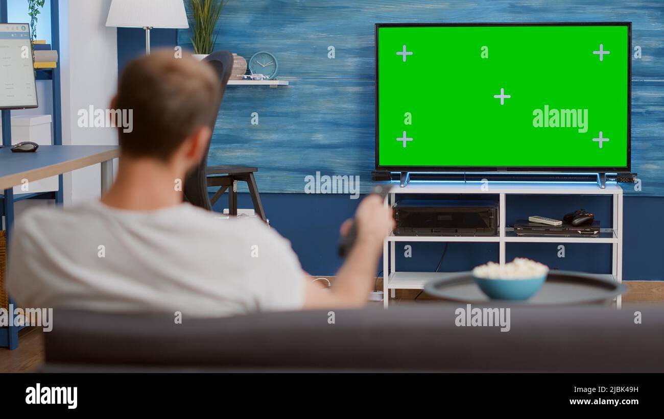 Static tripod shot of man switching channels while looking at green