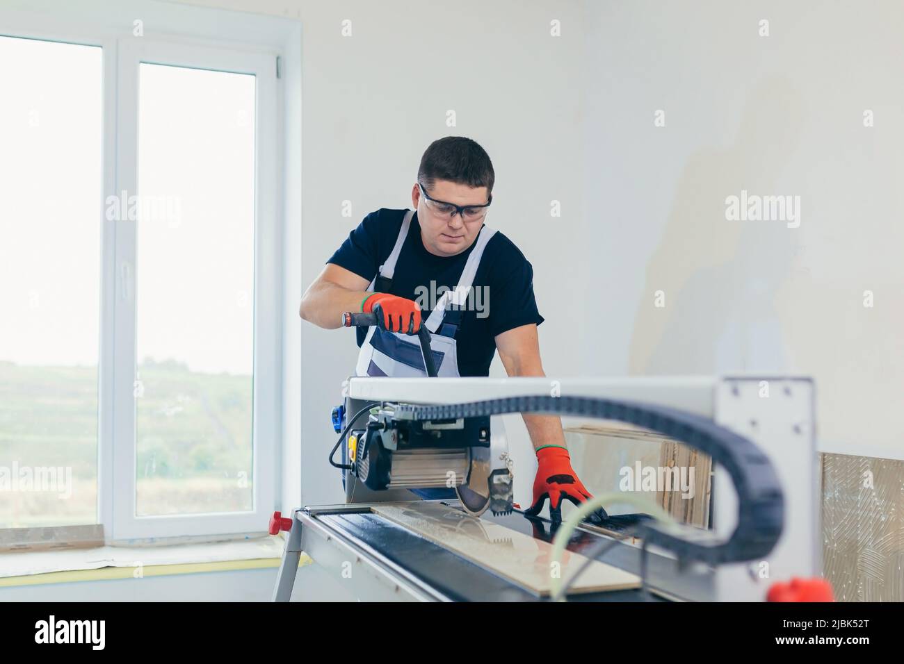 Master man, builder cuts a tile. Machine with a circular saw Stock Photo