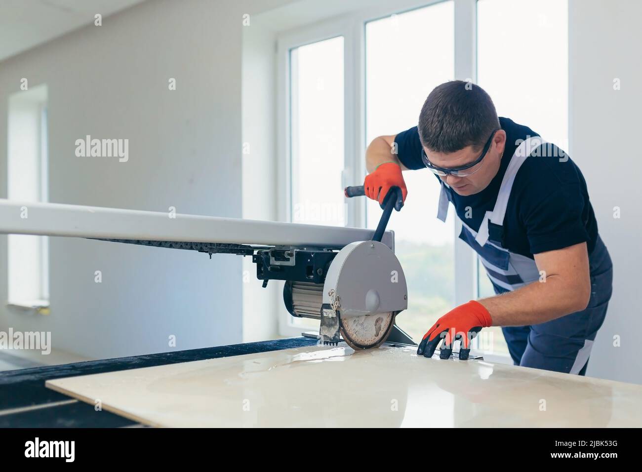 Master man, builder cuts a tile. Machine with a circular saw Stock Photo