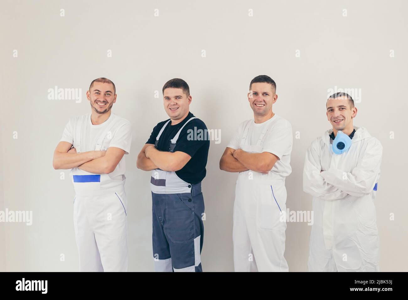 A team of construction workers, four people, men performing construction and repair work looking into the camera Stock Photo