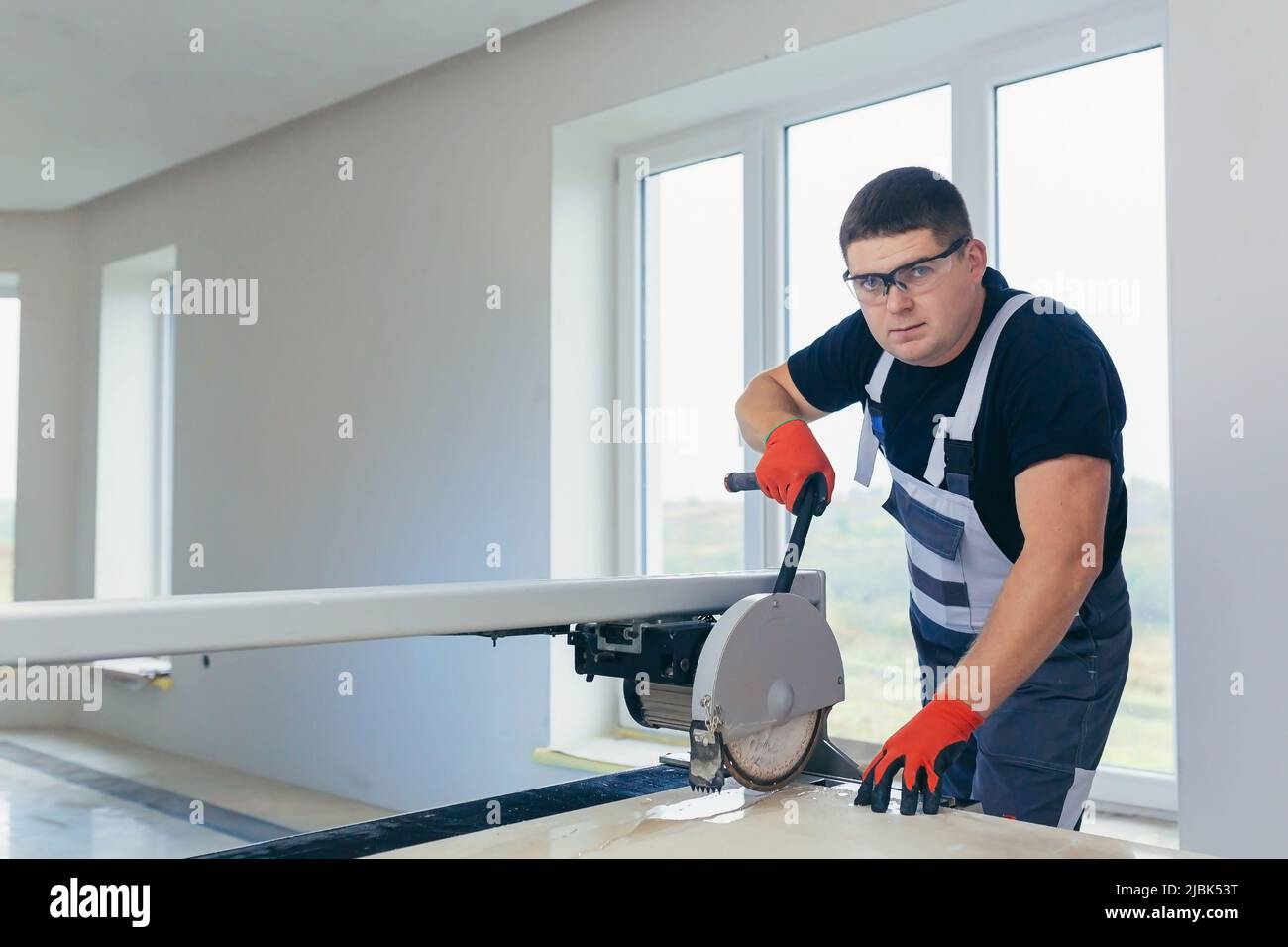 Master man, builder cuts a tile. Machine with a circular saw Stock Photo