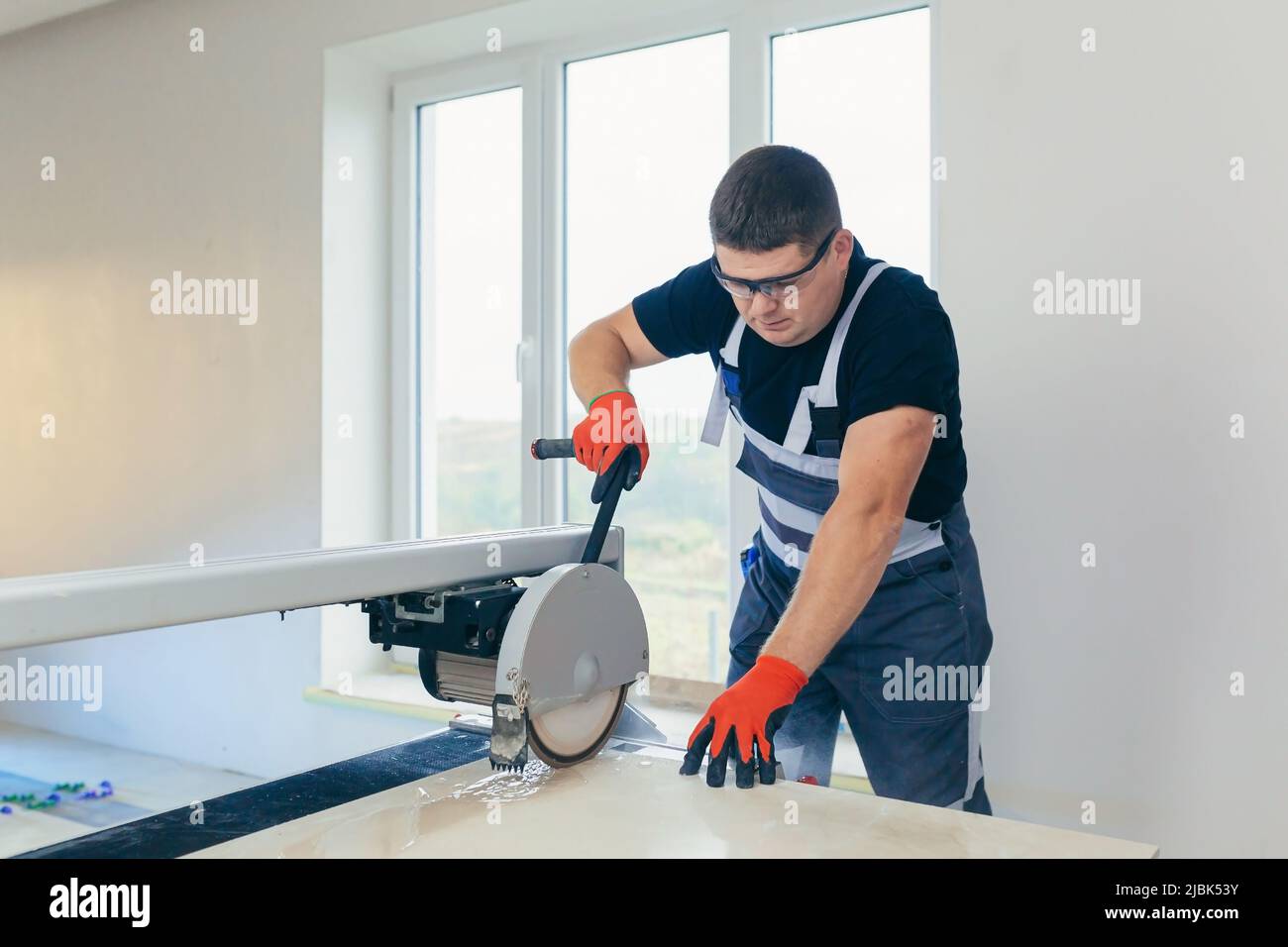 Master man, builder cuts a tile. Machine with a circular saw Stock Photo