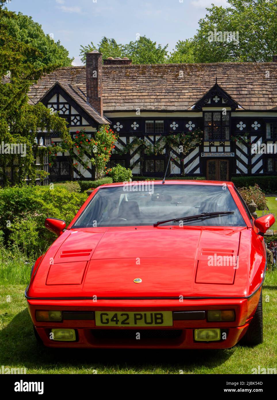 Red Excel Lotus with Gawsworth Hall in the background. Stock Photo