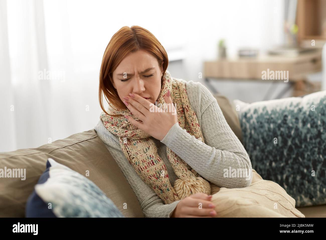 sick woman in scarf coughing at home Stock Photo